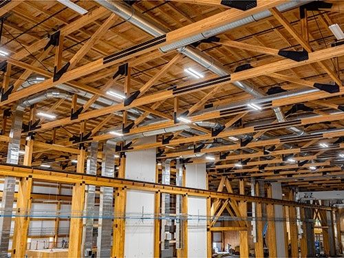 Holztragwerk mit Fachwerkträgern und Lüftungstechnik in einer großen Halle